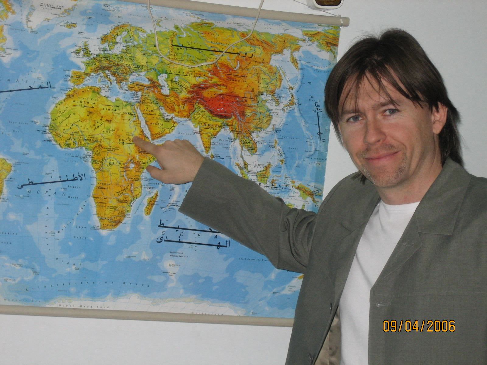 Patrik beside a world map, in a personal archive photograph dated 2006