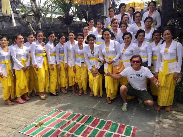 Visitors with a group wearing white and yellow ceremonial dress in Bali