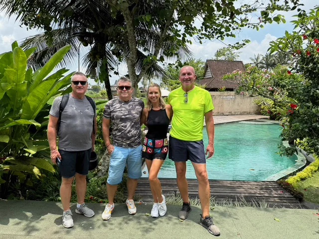 Four travellers beside a swimming pool and tropical garden