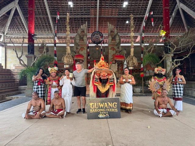 Travellers posing with performers in elaborate traditional costumes