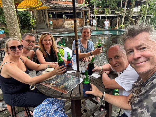 A group of travellers around an outdoor table in a tropical setting