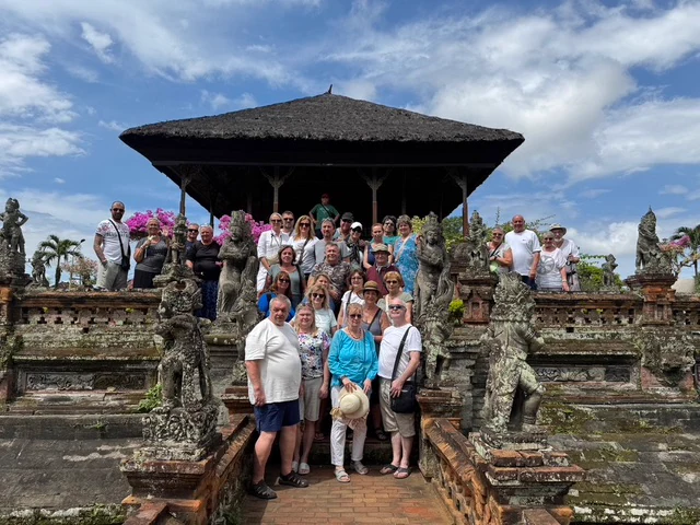 A group of travellers on stone steps in front of a Balinese temple pavilion