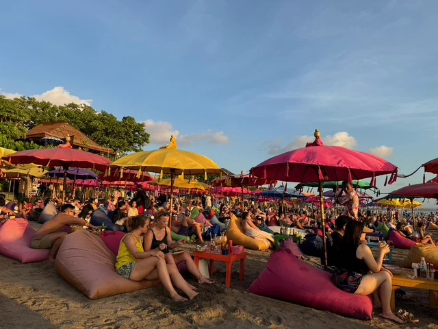 People relaxing on colourful seats beneath beach parasols