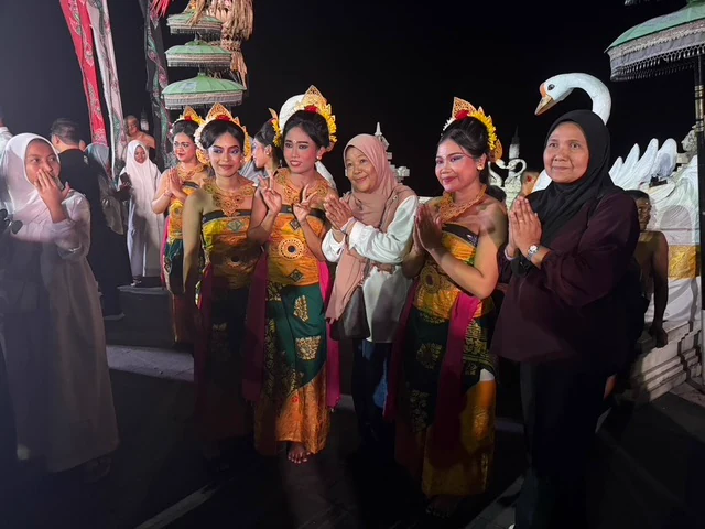 Visitors posing with performers wearing colourful traditional costumes at night